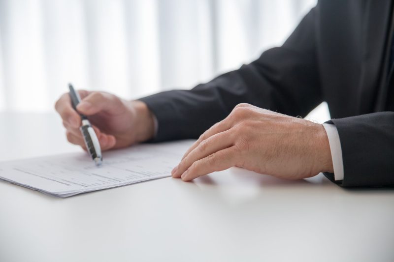 Businessman signing important documents at office desk
